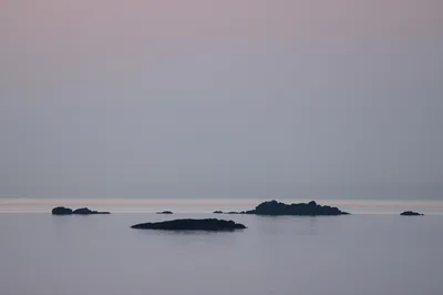 A calm sea with scattered rocks under a serene evening sky, offering a peaceful coastal view.