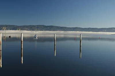 Peaceful scene of a boat on Clear Lake with mountains and blue sky.