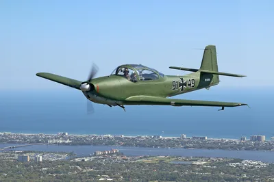 A vintage Piaggio P.149 warbird in Luftwaffe markings flying over the Florida coastline near Daytona Beach.