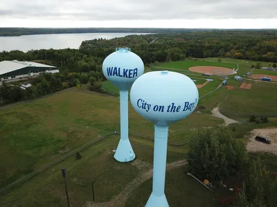 Aerial view of a Minnesota lakeside town with water towers and lush green forests