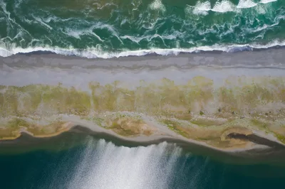Aerial view of a narrow strip of land between the Pacific Ocean and a freshwater lagoon on the Northern California coast.