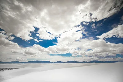 Wide view of White Sands National Monument with dramatic cloudscape and the Sacramento Mountains in the distance