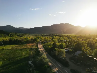 Aerial view of a road running west toward the snow-capped Front Range mountains in Boulder, Colorado at sunset.