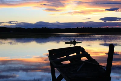 Serene lake view with silhouetted canoeist at sunset in Scarborough, Maine.