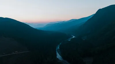 Aerial view of a winding river in a lush mountain valley in Washington State during twilight.