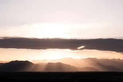 Breathtaking sunset casting rays over mountains in Cody, Wyoming with dramatic cloudscape.
