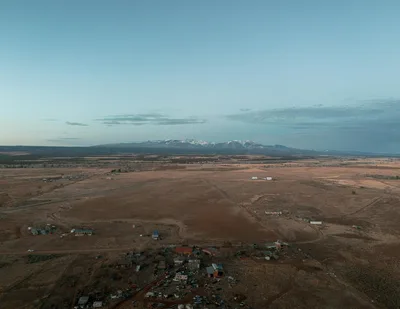 Aerial sunrise view of the Durango, Colorado valley floor with snow-capped San Juan Mountains in the distance.