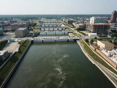 Aerial view of downtown Des Moines, Iowa, showcasing the river, bridges, and urban landscape on a clear day.