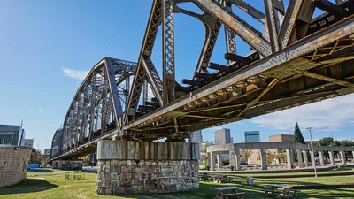 The Shreveport city skyline seen beyond a historic steel bridge over the Red River area.