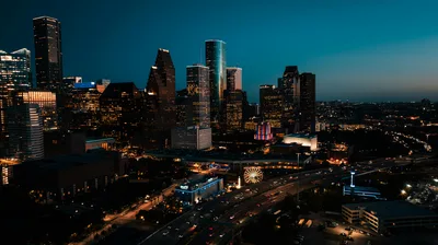 Aerial view of downtown Houston's illuminated skyscrapers at dusk.