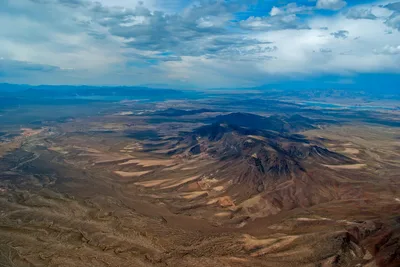 Dramatic aerial view of the rugged Nevada desert and mountain terrain under a cloudy sky.