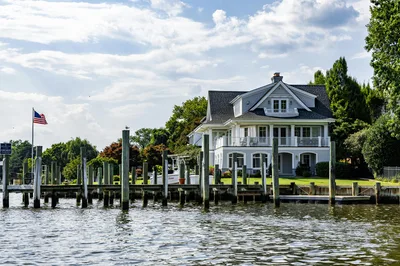 A lovely waterfront home with a dock and American flag on a sunny summer day.