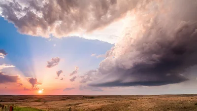 A dramatic sunset over the flat Kansas prairie with storm clouds on the horizon.