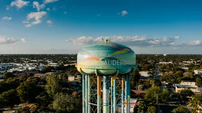 Aerial view of a vibrant water tower with 'Fort Lauderdale' written on it, surrounded by a lush urban landscape.
