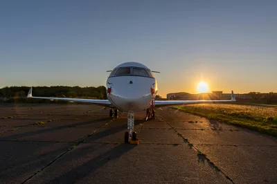 A high-end private jet parked on an airport ramp during a vibrant golden hour sunset, reflecting the upscale Million Air FBO experience at Stennis International.