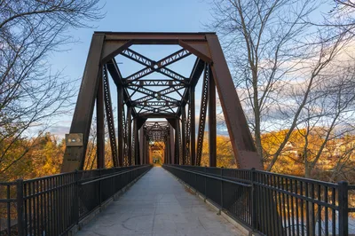 Beautiful fall scene of a historic railroad bridge in Auburn, Maine with vibrant autumn foliage.