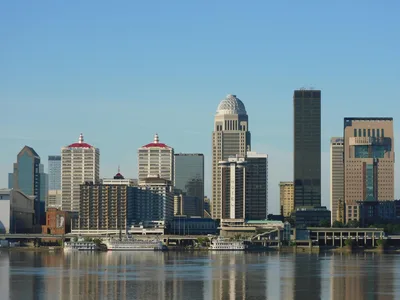 Panoramic view of the Louisville, Kentucky skyline reflecting off the Ohio River at dusk.