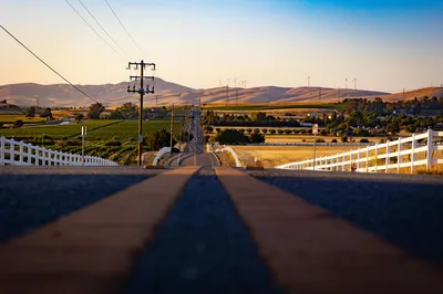 A scenic road winding through Livermore vineyards and hills at sunset, with wind turbines on the horizon.
