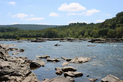 Scenic view of the Potomac River with rocky banks and lush green hills at Harpers Ferry, near Martinsburg, West Virginia.