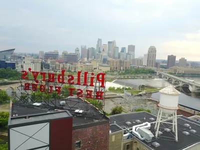 Aerial view of the Minneapolis skyline and Mississippi River with iconic historic signs.