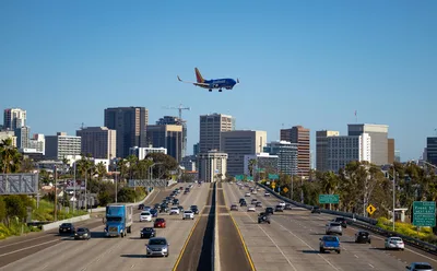 Airplane approaching San Diego over a busy city freeway with the skyline in the background.