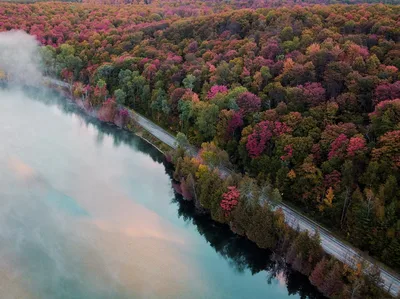 Aerial view of a misty lake and vibrant autumn forest in Northern Michigan