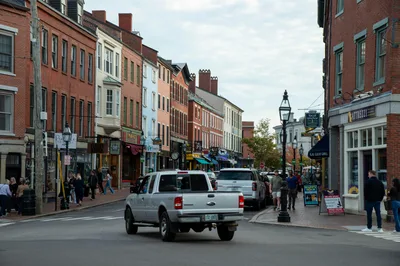 Vibrant street view of downtown Portsmouth, New Hampshire, with historic brick architecture and people walking on a sunny day.