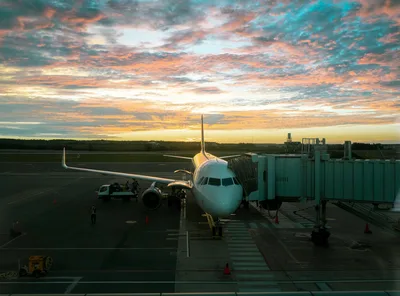 A sleek private jet on the ramp at an airport during a vibrant golden hour sunset.