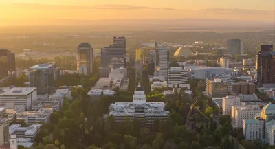 Aerial view of Sacramento cityscape featuring the California State Capitol and Tower Bridge at sunset