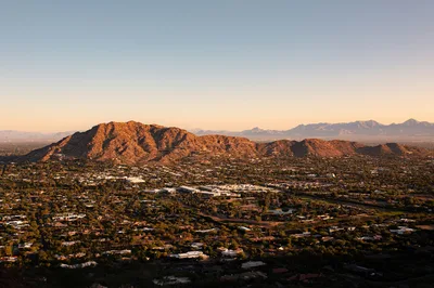 Aerial golden hour view of the Scottsdale valley with Camelback Mountain and the McDowell Mountains in the background.
