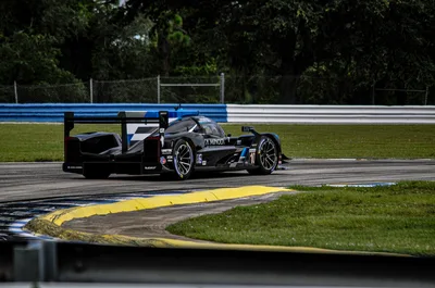 A high-speed race car navigating a turn at the Sebring International Raceway, adjacent to the airport.