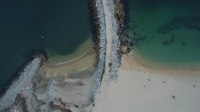 Aerial shot of a breakwater on the beach in Santa María Huatulco, showcasing turquoise waters.