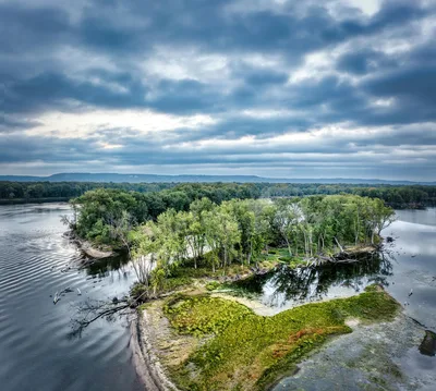 Aerial view of the Mississippi River landscape in Minnesota with lush green river islands and scenic clouds.