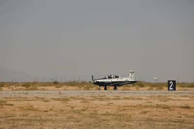 A T-6 Texan II military trainer aircraft sitting on the flight line in a dry South Texas landscape