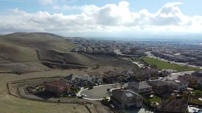 A scenic aerial view of a hillside residential neighborhood in Dublin, CA under a bright sky.