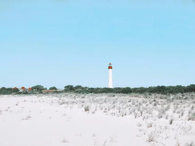 The iconic Cape May Lighthouse surrounded by sand dunes under a clear blue sky