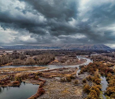 Aerial view of the Yakima River surrounded by rugged wilderness and dramatic clouds in fall.