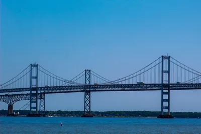 Wide view of the Chesapeake Bay Bridge crossing the blue water of the bay under a clear sky.